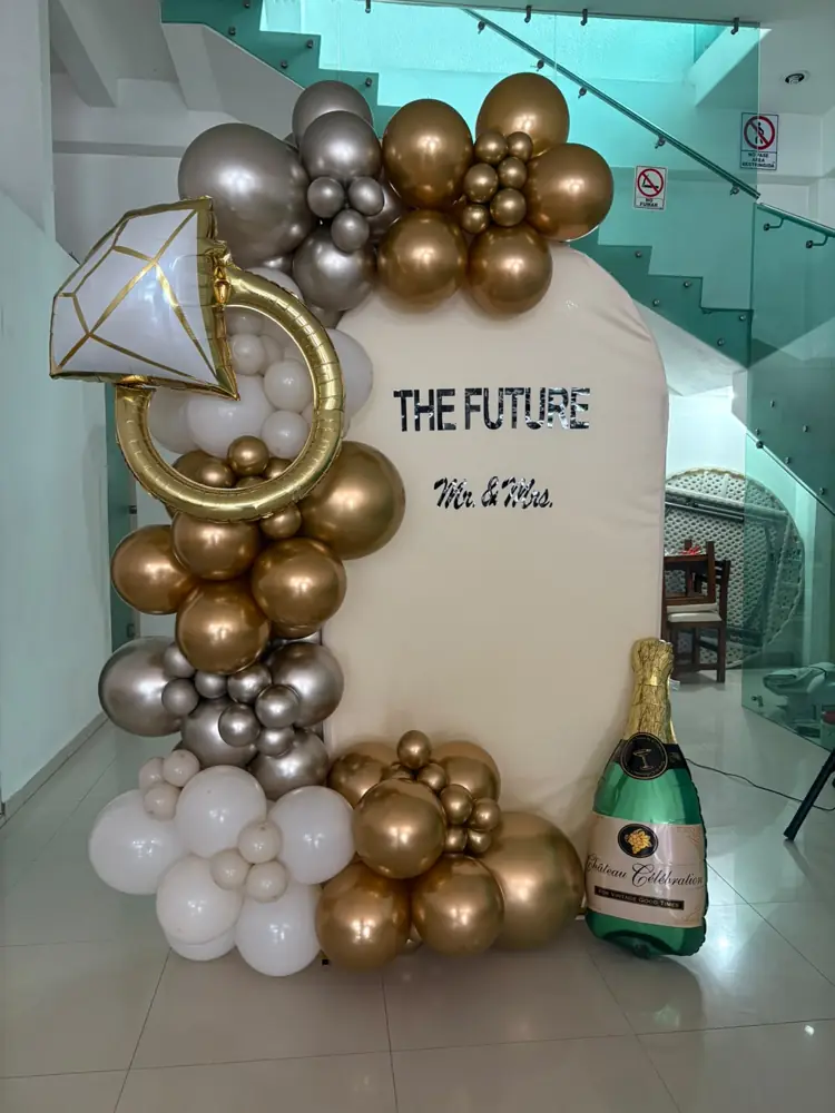 Mampara con globos dorados, botella de champán y anillo